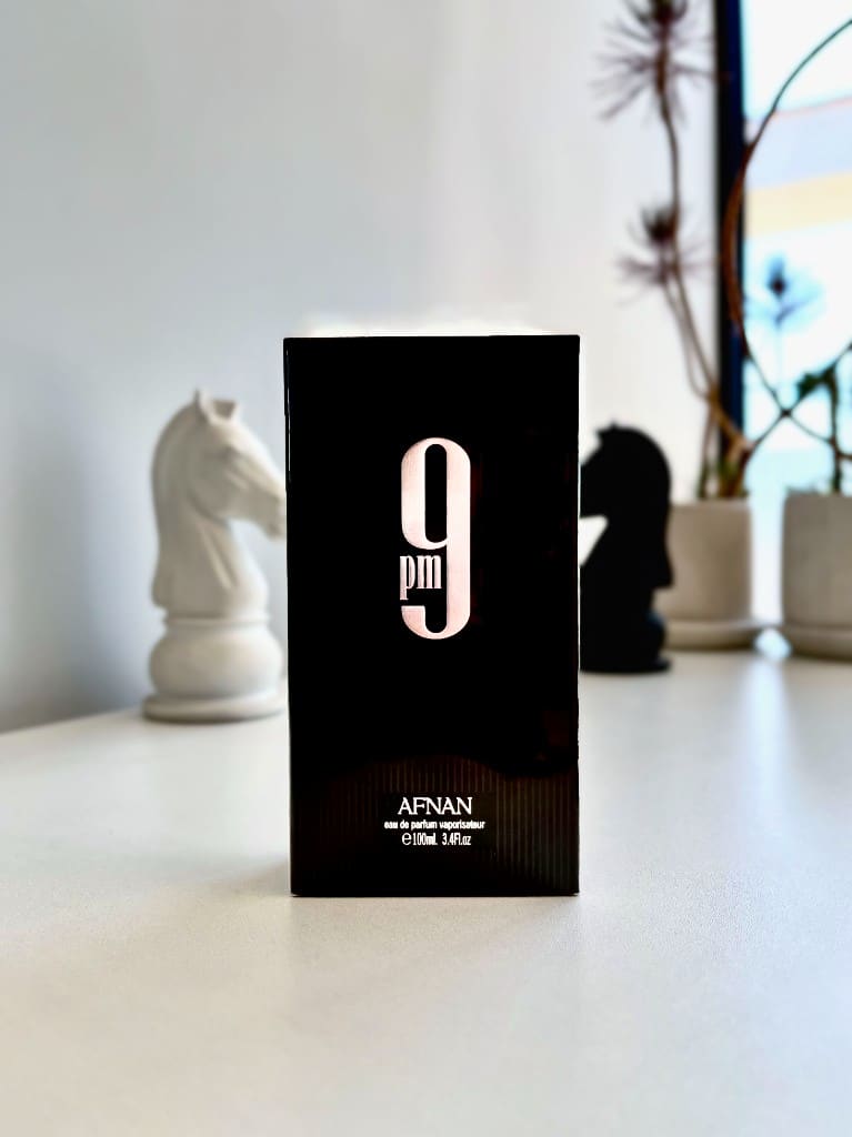 Caja negra del perfume 9 PM de Afnan con fichas de ajedrez de fondo